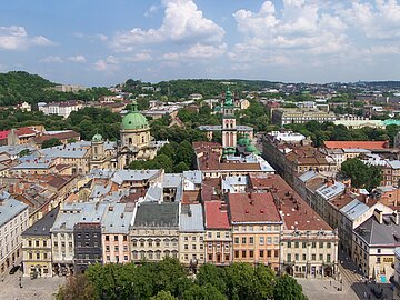Welterbe_Lwiw_CC-BY_Lestat_Jan_Mehlich Blick von oben auf die Stadt Lwiw. Man sieht viele alte, schöne Häuser, zentral ein sakrales Kuppelgebäude und im Hintergrund grüne Hügel.