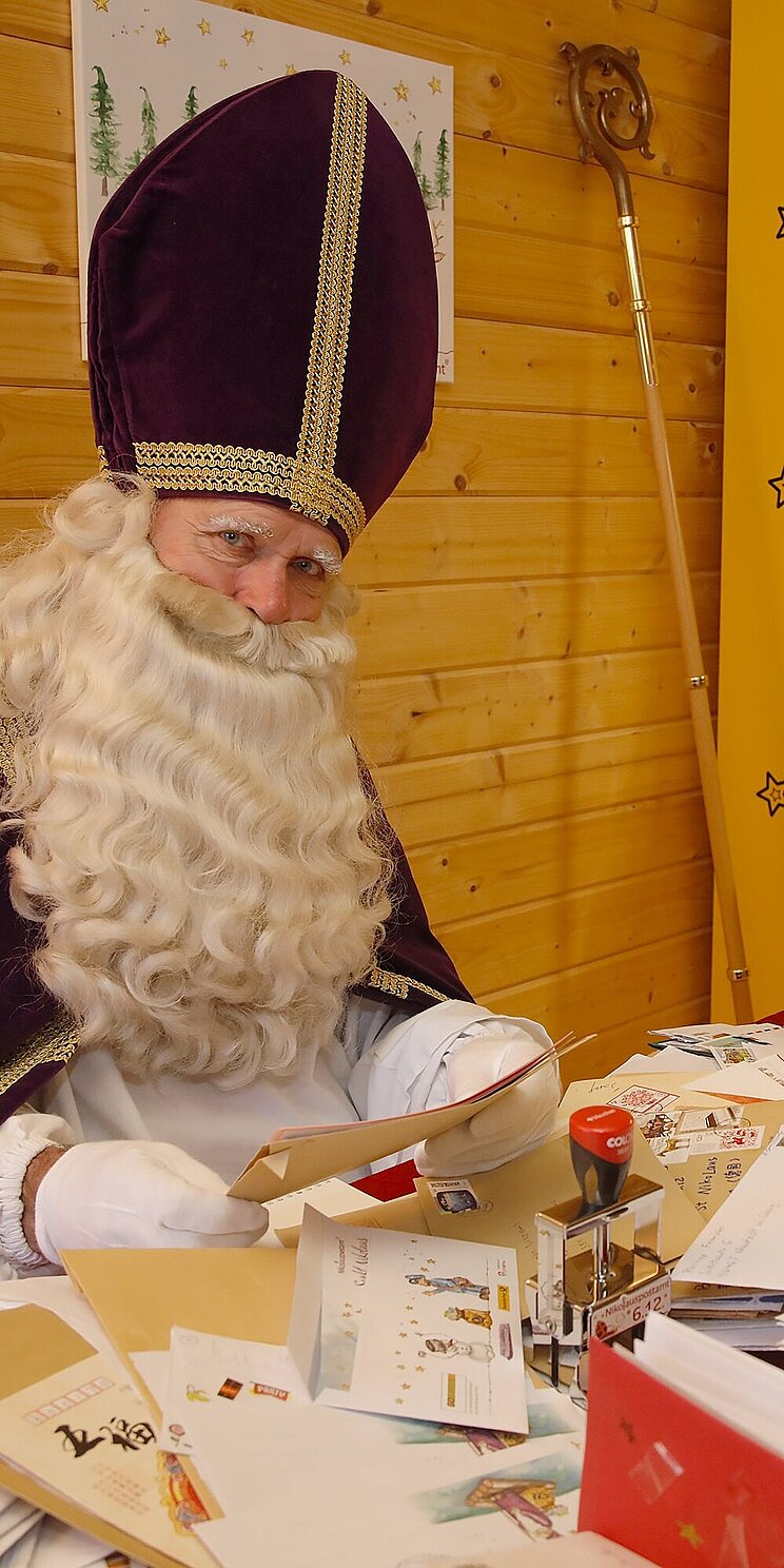 02_Nikolauspostamt_Briefe_an_den_Nikolaus Person als Nikolaus verkleidet hält Kinderbriefe in den Händen