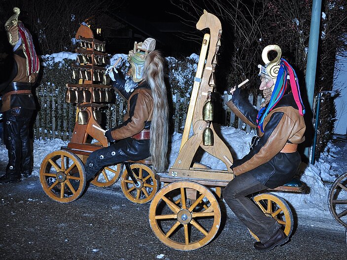 Zwei Personen begleiten den Perchtenlauf auf speziellen Glockenspiel-Wägen.