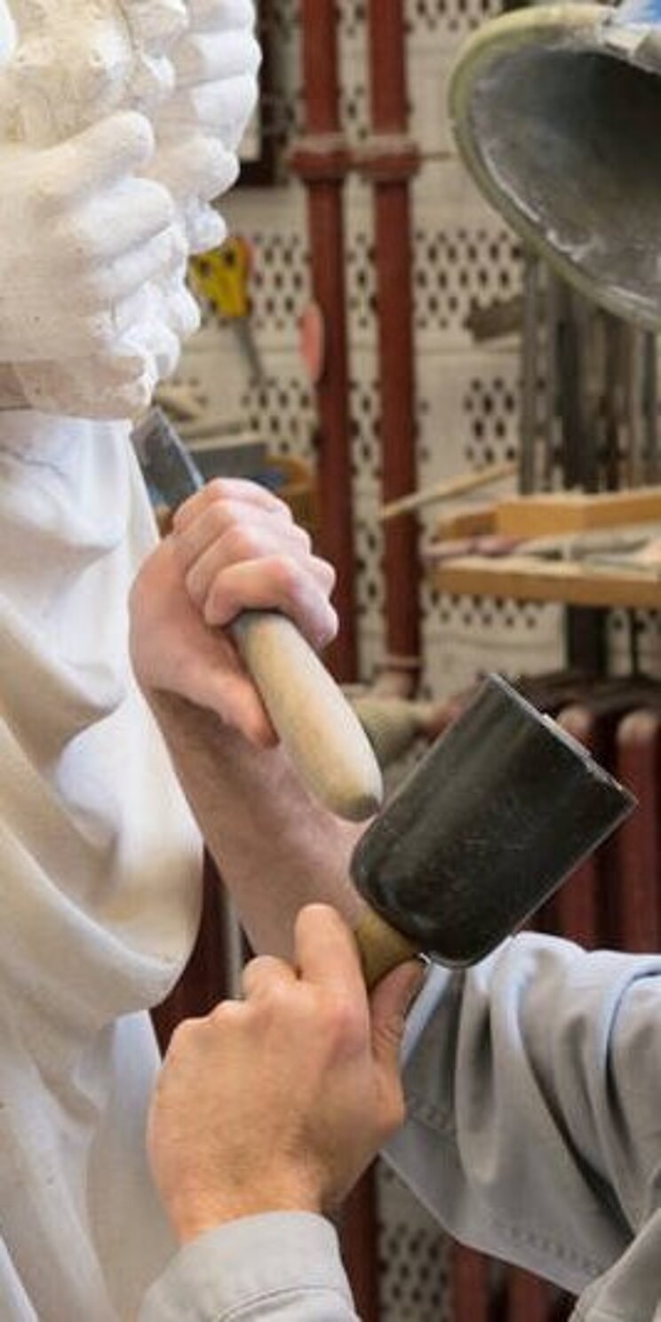 002-BAUHUETTE-Bildhauer_Hoppe_c_Dombauarchiv_Koeln Handwerker beschlägt eine Statue mit Hammer und Meißel