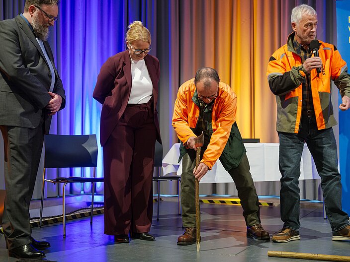 Urkundenverleihung_25_Gehöferschaft_Wadrill Ministerin Streichert-Clivot und Vorsitzender des Fachkomitees schauen sich die Vorführung einer Zuteilung der Gehöferschaft an. Die Trägergruppe trägt Arbeits-/Waldkleidung