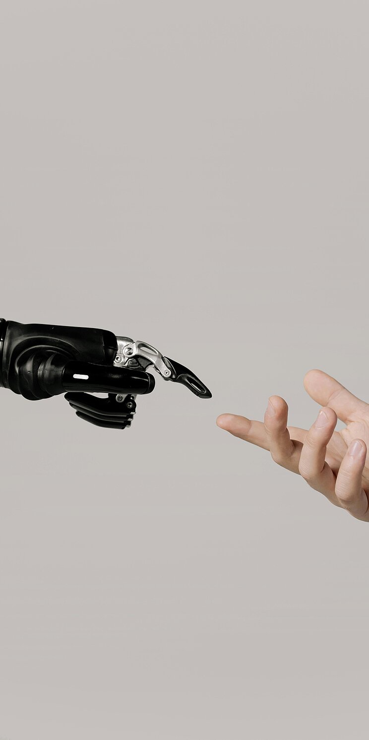 Roboterhand und menschliche Hand kurz vor Berührung