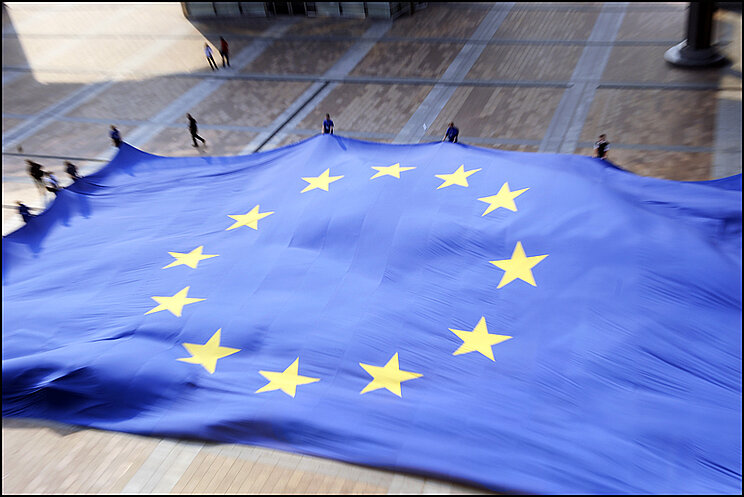 Europaflagge Viele Menschen spannen auf einem Platz eine übergroße Europaflagge auf.