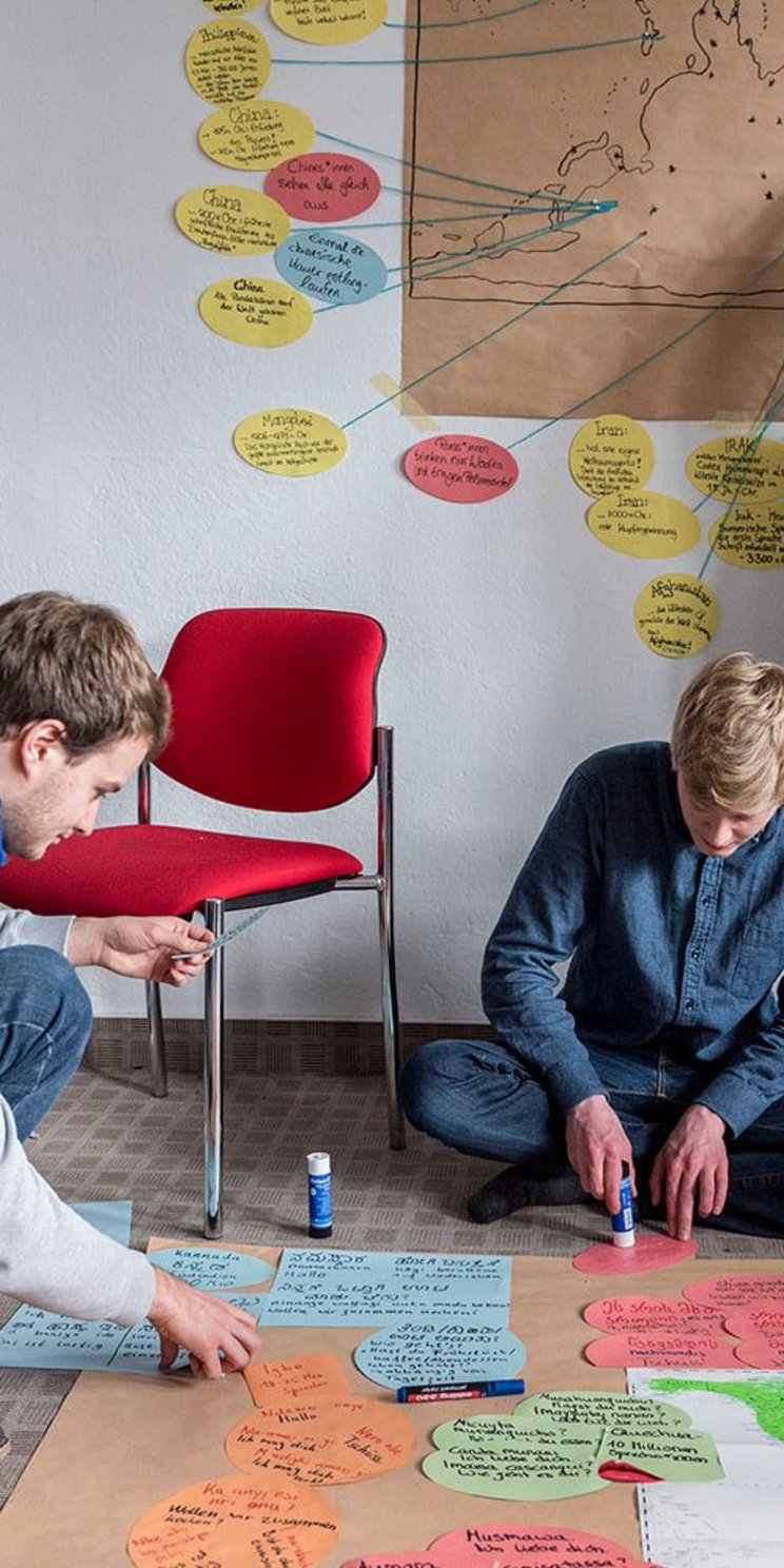 Junge Menschen arbeiten gemeinsam an einer Weltkarte.