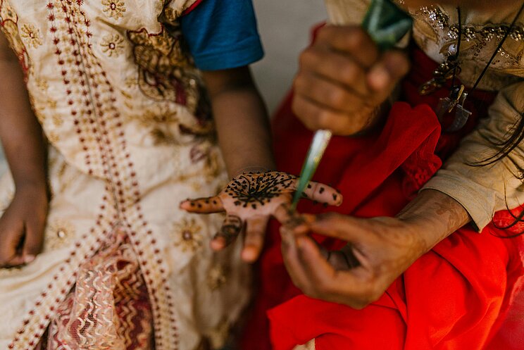 Henna als Immaterielles Kulturerbe Blick auf eine zentrierte Handfläche, auf der Muster mit einer Farbtüte gezeichnet werden.