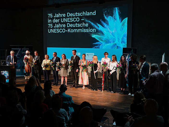 Auf der B&uuml;hne stehen alle Menschen, die eine aktive Rolle beim Festakt hatten zu einem Gruppenbild zusammen