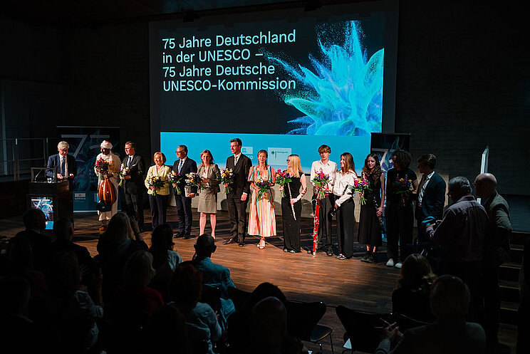 Auf der B&uuml;hne stehen alle Menschen, die eine aktive Rolle beim Festakt hatten zu einem Gruppenbild zusammen