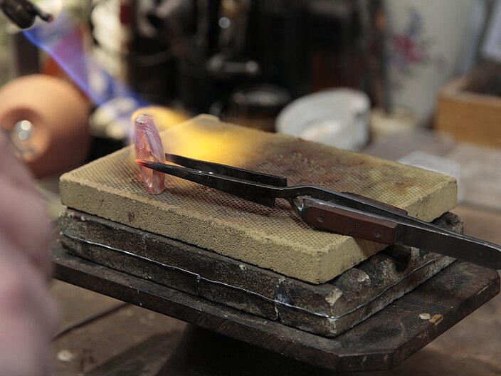 Ein Stück Metall wird in einer Zange mithilfe der Mokume Gane Technik durch erhitzen verschweißt.