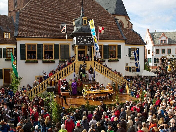 Menschenmenge steht draußen vor dem Diedesheimer Rathaus. Tribüne wurde errichtet auf der kostümierte Menschen sitzen und das Stadtgericht nachspielen.