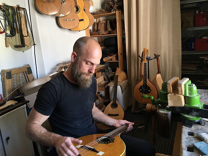 Waldzither-Bauer in seiner Werkstatt untersucht eine Waldzither