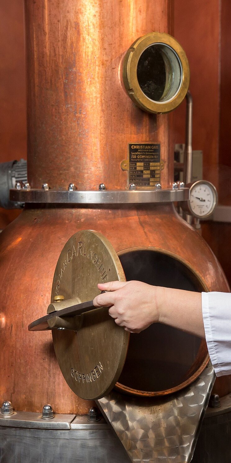 Brennerin öffnet Tür des Brennofens um Destillationsprozess zu überprüfen.