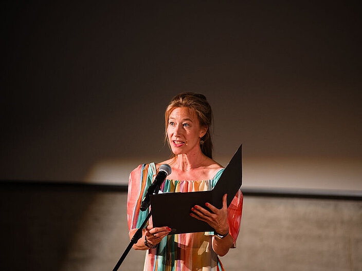 Johanna Wokalek steht auf einer B&uuml;hne und rezitiert einen Text