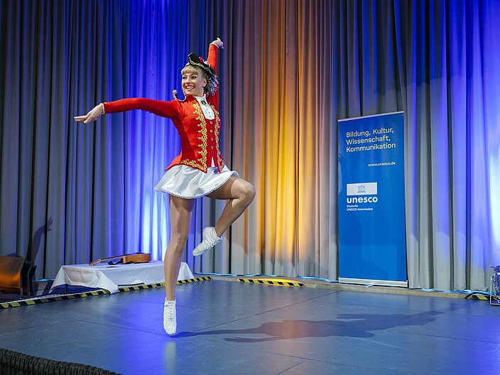 Urkundenverleihung_25_Tanzmariechen Tanzmariechen in roter Uniform tanzt Solo auf der Bühne