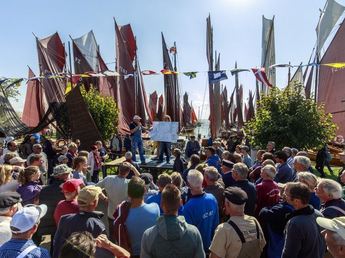Menschengruppe steht vor Booten im Hafen