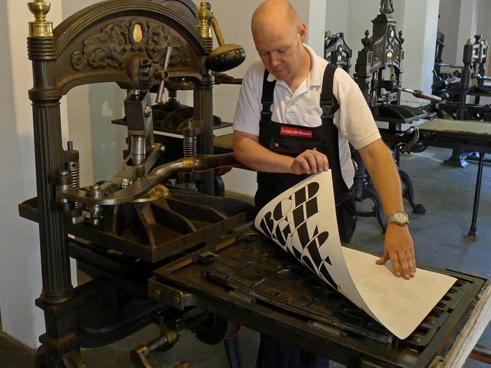 Drucker an einer antiken Druckpresse