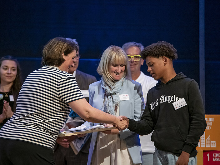 Urkundenübergabe ARP Auf diesem Bild übergibt Frau Ruyter-Petznek vom Bundesbildungsministerium eine Auszeichnungsurkunde an einen Jugendlichen