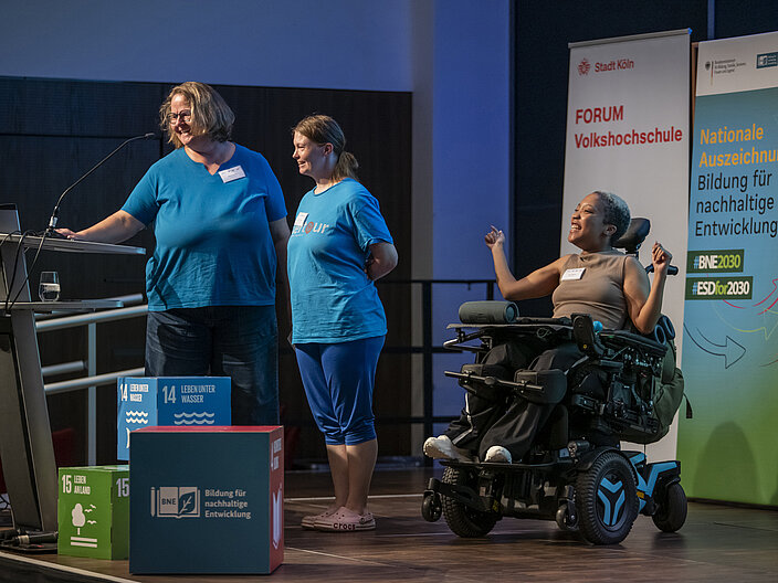 BNE Auszeichnung Köln PIKSL Labor AUs fiesem Foto sind Menschen mit und ohne Behinderung während ihres Beitrags zu digitaler Teilhabe auf der Bühne zu sehen