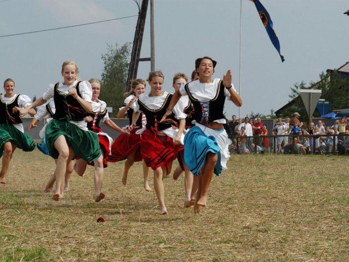 Frauen in Tracht rennen barfuß über eine Wiese