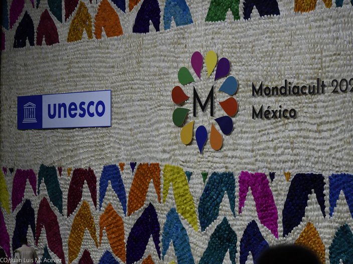 Bunt gestaltete Wand mit dem Logo der UNESCO und der Weltkulturkonferenz Mondiacult 2022. 