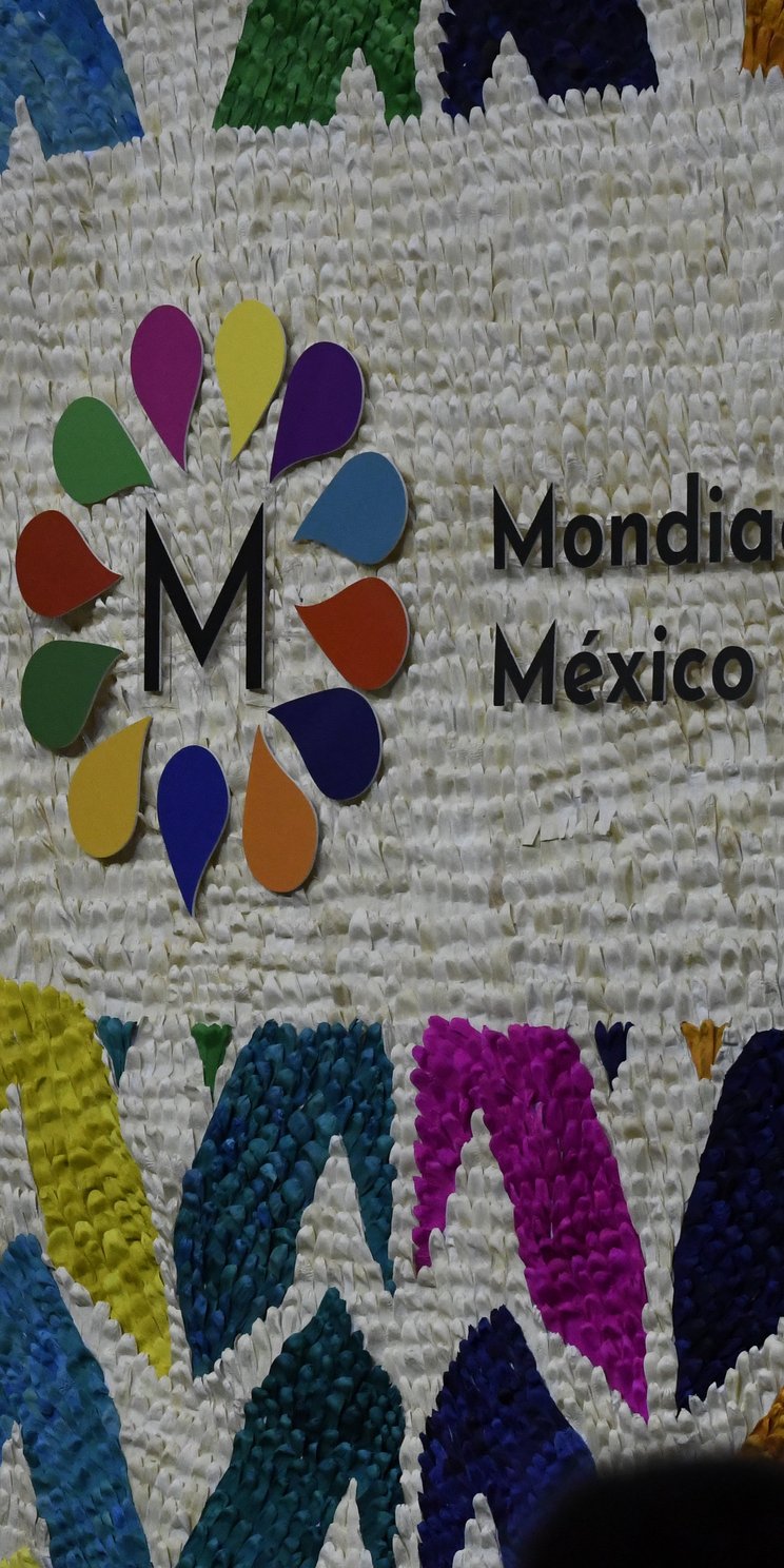 Bunt gestaltete Wand mit dem Logo der UNESCO und der Weltkulturkonferenz Mondiacult 2022. 