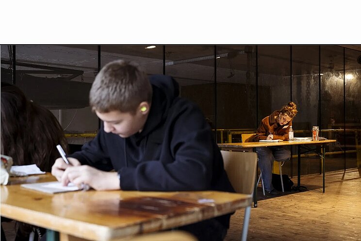 Zwei junge Menschen am Schreibtisch die etwas aufschreiben