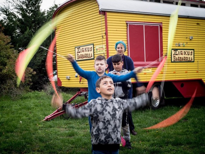 Kinder üben mit bunten Bändern vor einem Wohnwagen