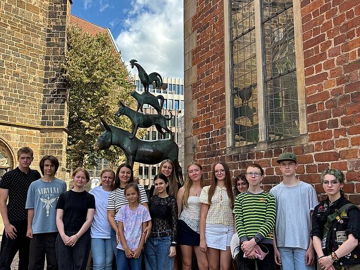 Eine Schülergruppe des Recreation-Projekts aus Verden steht vor den Bremer Stadtmusikanten in Bremen
