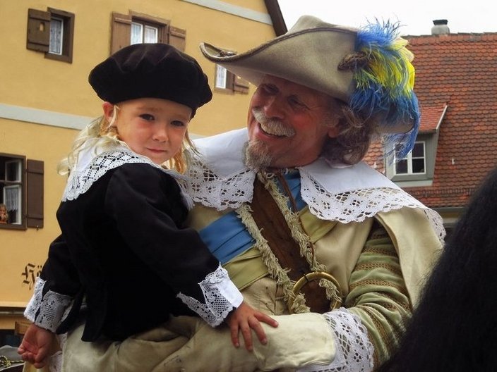 Mann in historischem Kostüm mit Kind auf dem Arm