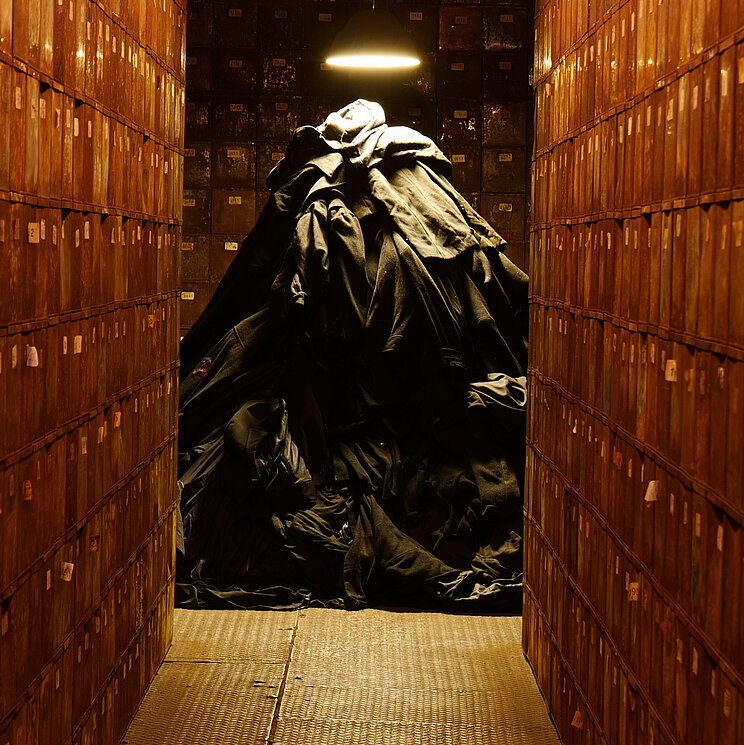 Ein aufgetürmter Haufen von Habseligkeiten von Zwangsarbeitern zwischen alten Spinden in der Völklinger Hütte