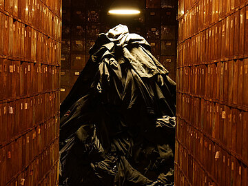 Ein aufgetürmter Haufen von Habseligkeiten von Zwangsarbeitern zwischen alten Spinden in der Völklinger Hütte