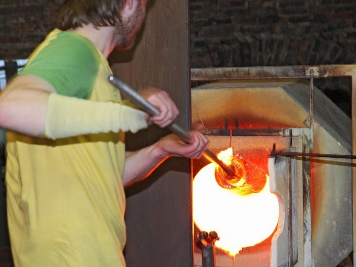 Glasbläser erhitzt Glas in einem Ofen