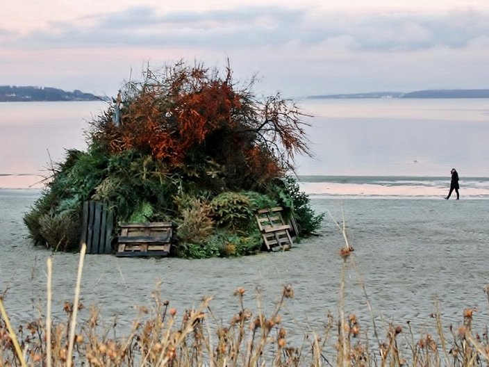 Etwa vier Meter großer Haufen aus Gras und Holz am Strand