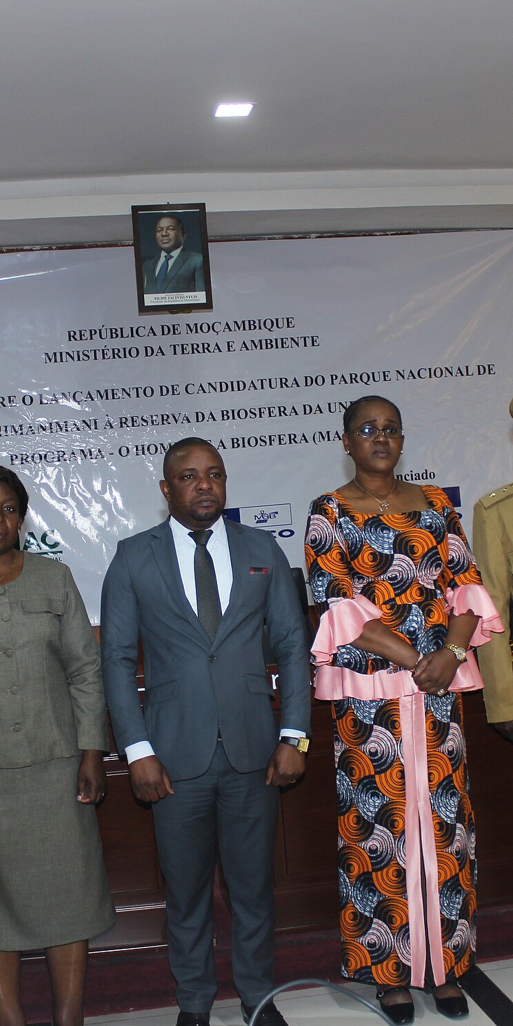 2 women and 6 men are standing side by side in front of a banner. The banner reads Workshop on the nomination process of the Chimanimani National Park as a UNESCO Biosphere Reserve (in Portuguese).