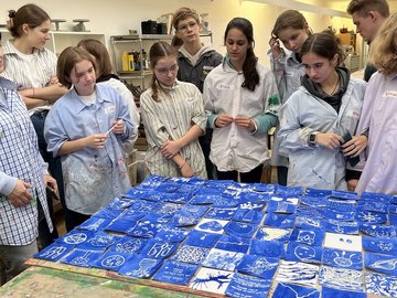 Ukrainische Schüler und Schülerinnen stehen um einen Tisch herum und schauen auf die in einem Kunstworkshop kreierten Blaudrucke.