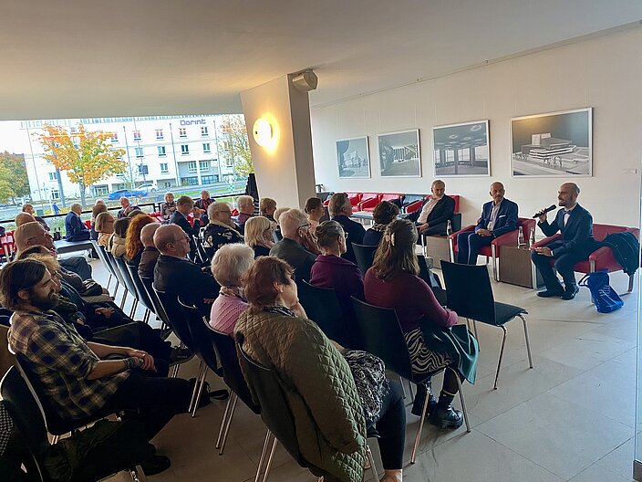 Raumperspektive der Veranstaltung. Zu Kopf sitzen die Sprechenden dem Publikum zugewandt