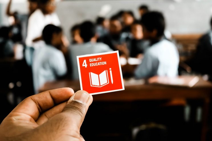 Globale Bildungsagenda: SDG 4 Eine Hand hält eine rote Karte, auf der Quality Education steht.