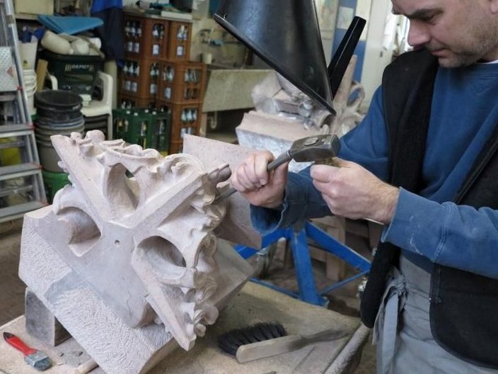 Handwerker bearbeitet schmuckvoll gearbeiteten Stein. 