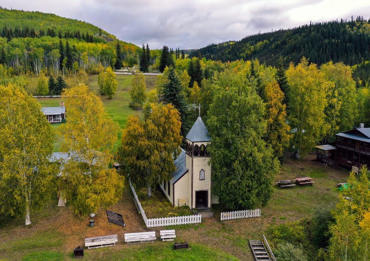 Klondike_c_GroundTruth_Exploration_Inc Das Bild zeigt eine Kirche, umgeben von einer bewaldeten Hügellandschaft