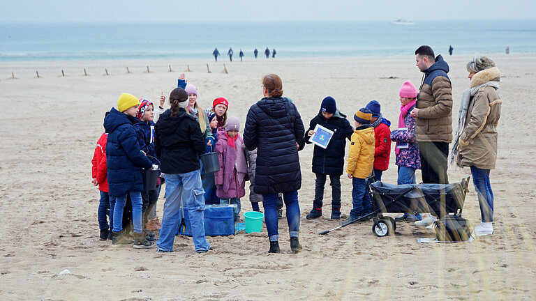 Auf diesem Bild sind Mitarbeitende des DRK bei einem Projekt mit Kindern am Strand zu sehen