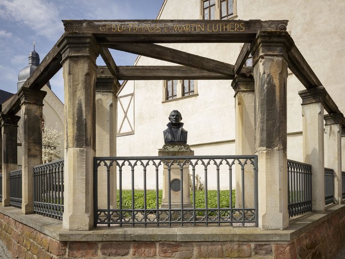 Blick auf Luthers Geburtshaus in Eisleben mit Lutherbüste im Vorgarten
