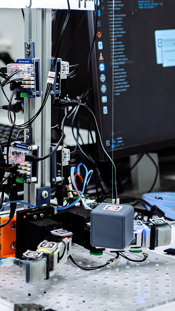 Robotik Schreibtisch mit verschiedenen wissenschaftlichen Geräten und Computerbildschirmen, die einen Robotik-Aufbau zeigen