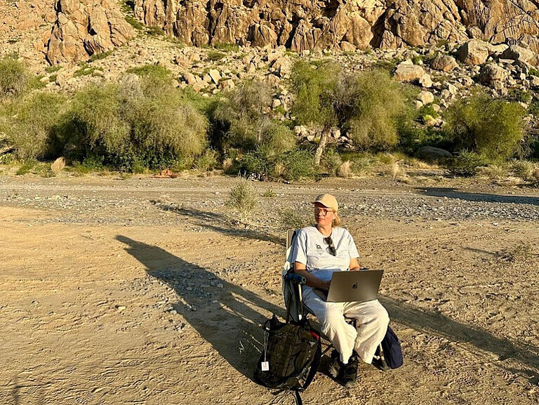 Julia Schnitzer mit Laptop vor einer Berglandschaft