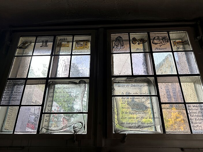 Blick durch zwei Fensterscheiben, die mit Humpisch Schriftzügen und Bildern verziert wurden.