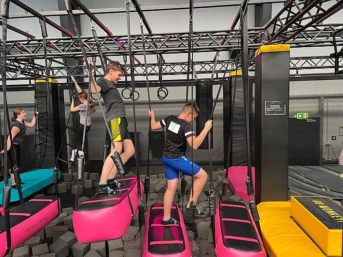 Vier ukrainische Schüler*innen klettern in einem Indoor-Seilgarten.
