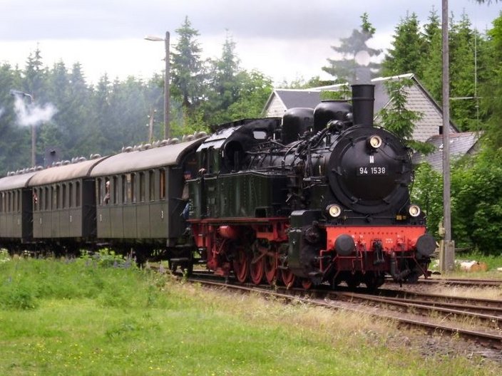 Dampflok mit Waggons vor Waldlandschaft