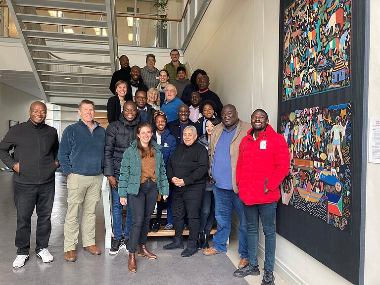 TTT Capetown 2023 Participants and organisers of the Train The Trainer workshop in Cape Town. The 20 or so people are standing on a staircase and smiling at the camera.