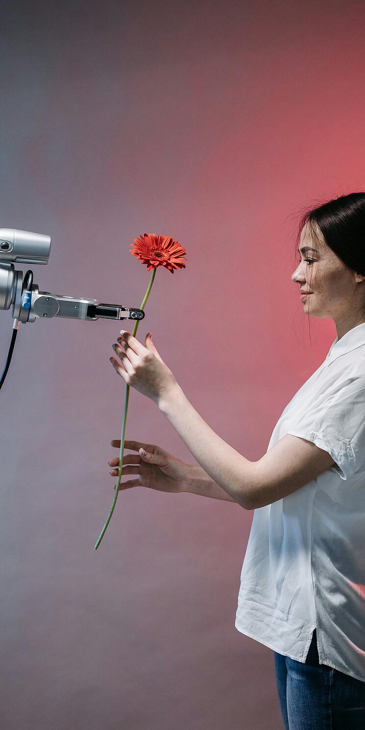 Ein Roboterarm reicht einer Frau eine Blume.
