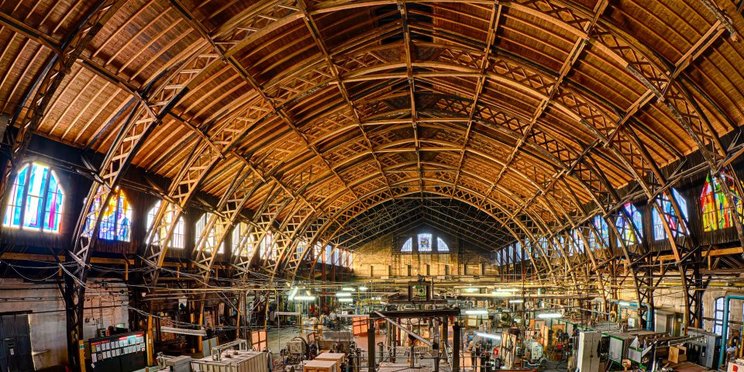 Ofenhalle Lamberts Waldsassen Das Bild zeigt eine Fabrikhalle mit zahlreichen Maschinen, die zur Glasproduktion verwendet werden.