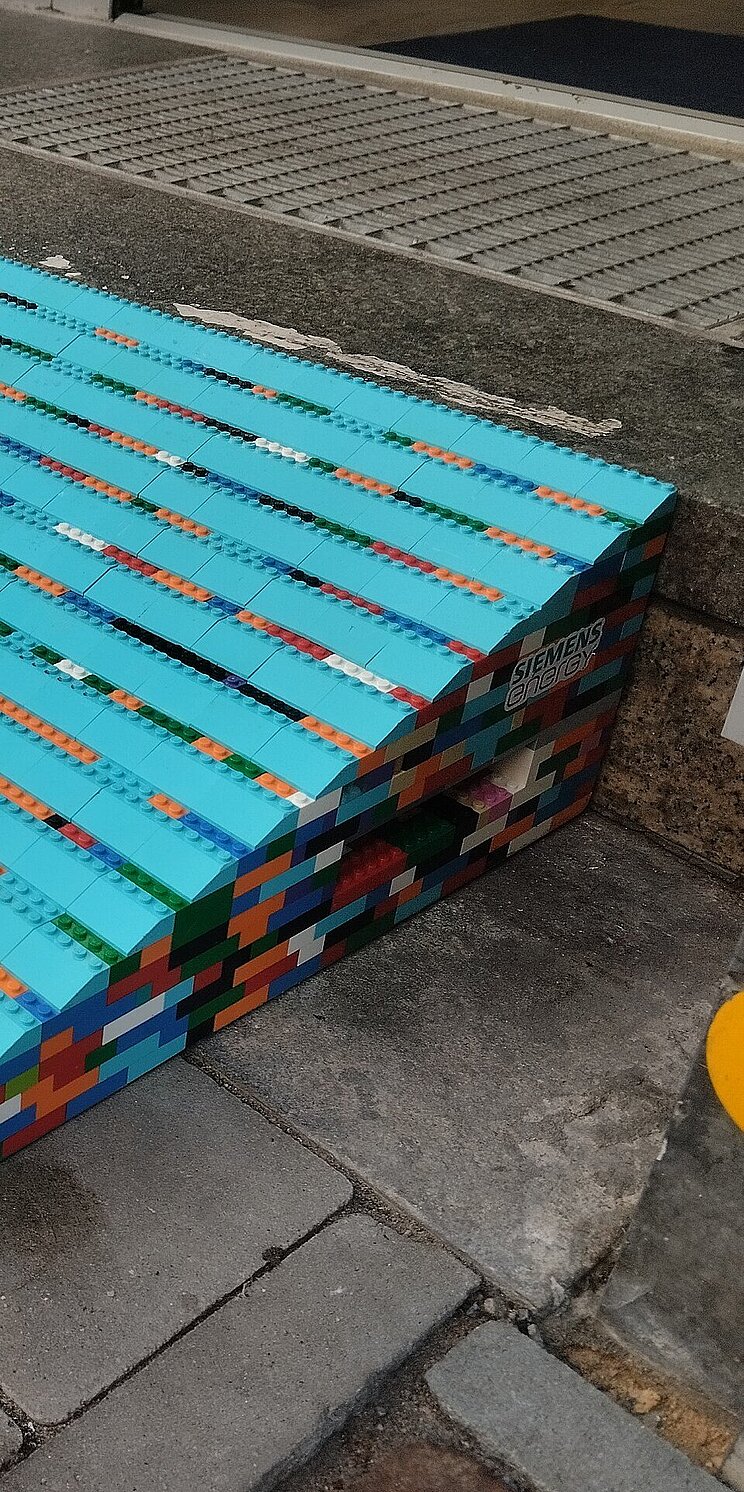 Eine aus bunten Legosteinen gebaute Rampe an einer Stufe im öffentlichen Raum