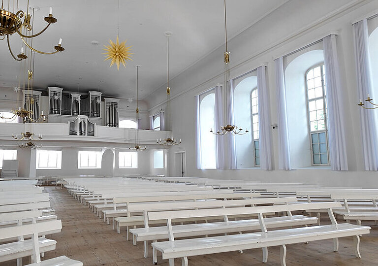 Blick in den in weiß gehaltenen Kirchensaal in Herrnhut